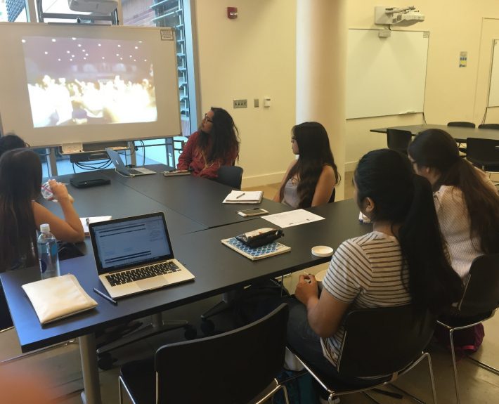 At the Learning Pavilion - Students seated around a table and watching a presentation on the projector screen