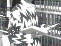 Click to show details - 00s - 4 student reading a book beside book shelves