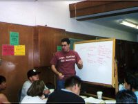Click to show details - 90s - 4 student speaking while standing at whiteboard