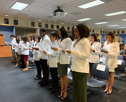 An image of High Aims Cohort members reading off of a piece of paper indoors.