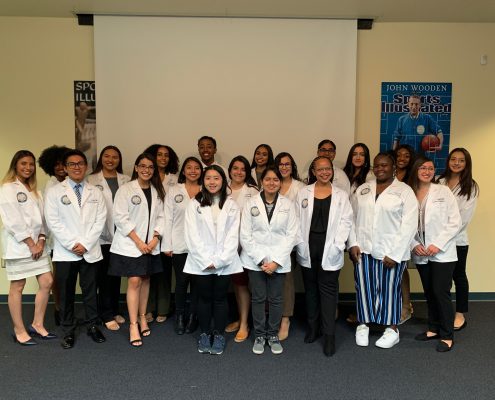 An image of the High Aims Cohort as a group indoors wearing their white coats.